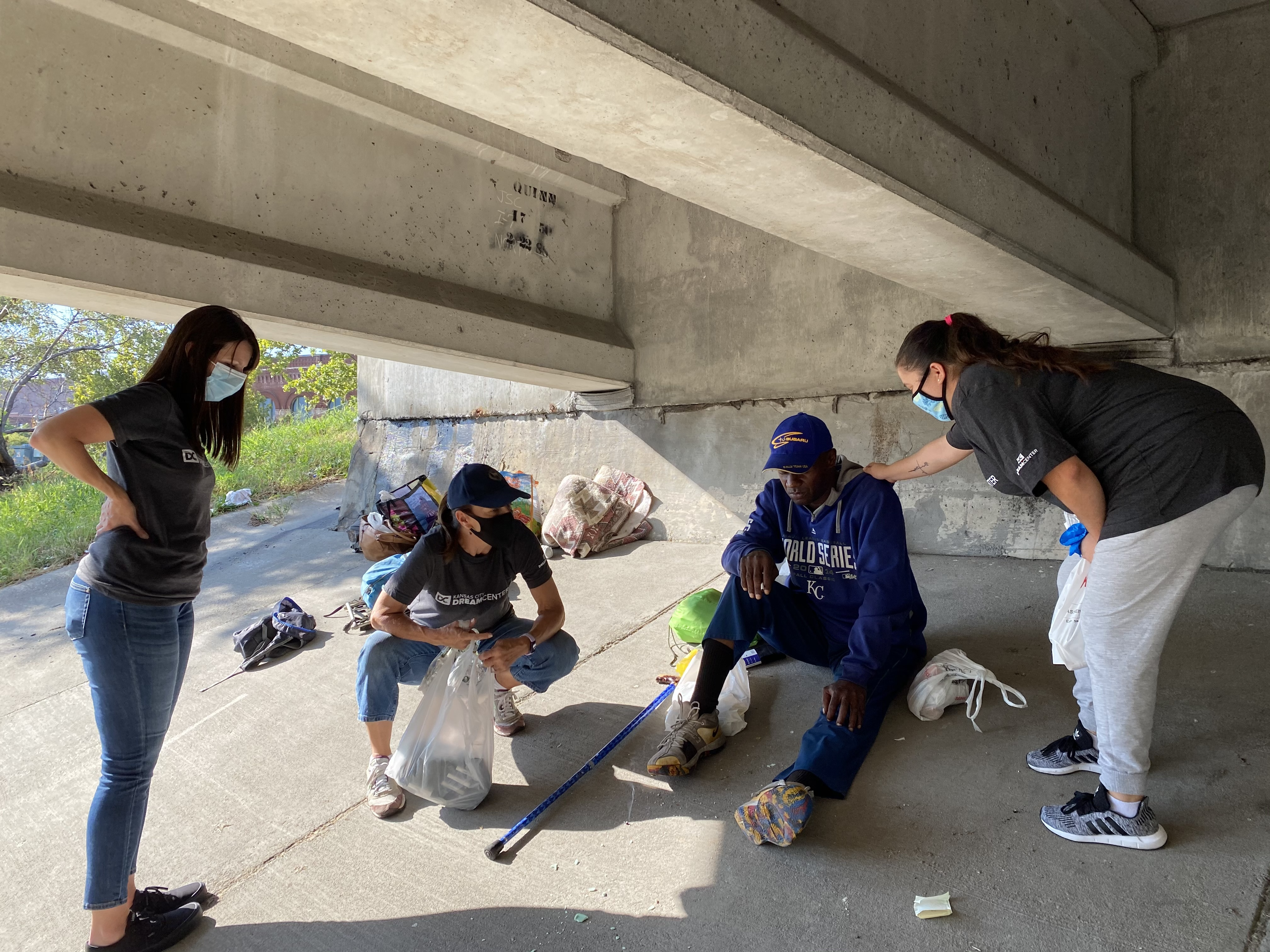 Volunteers and staff praying with a homeless individual during street outreach.